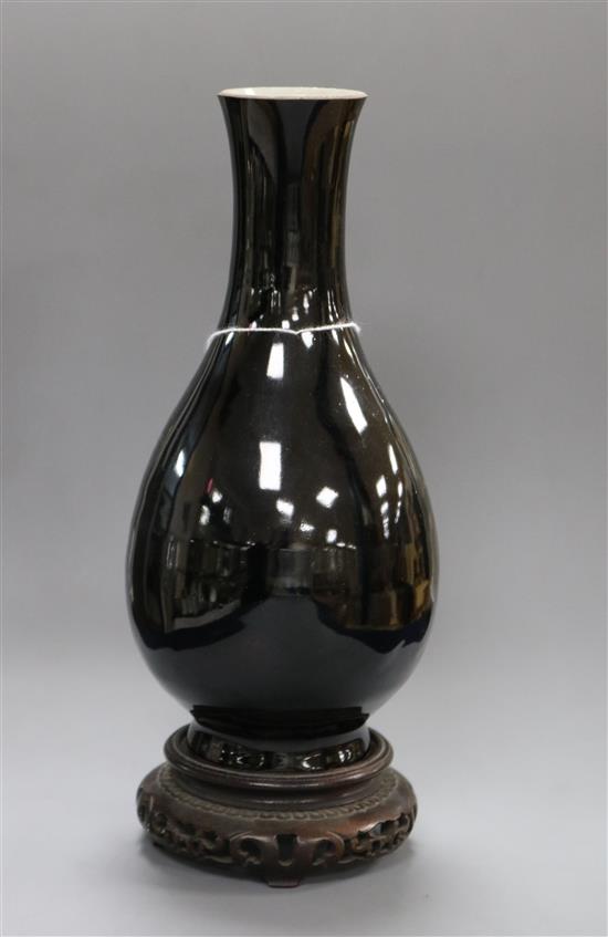 A 19th century Chinese black glazed bottle vase, wood stand